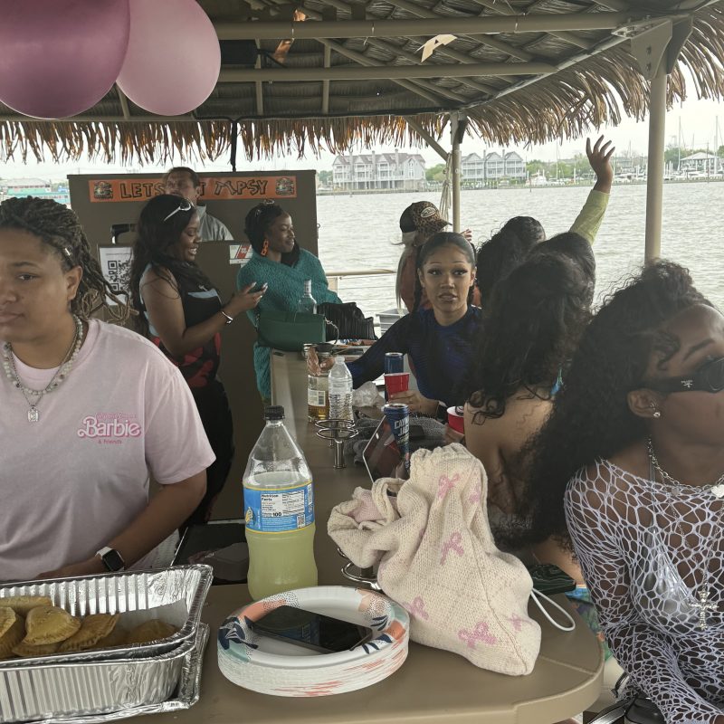a group of people sitting at a table with a birthday cake